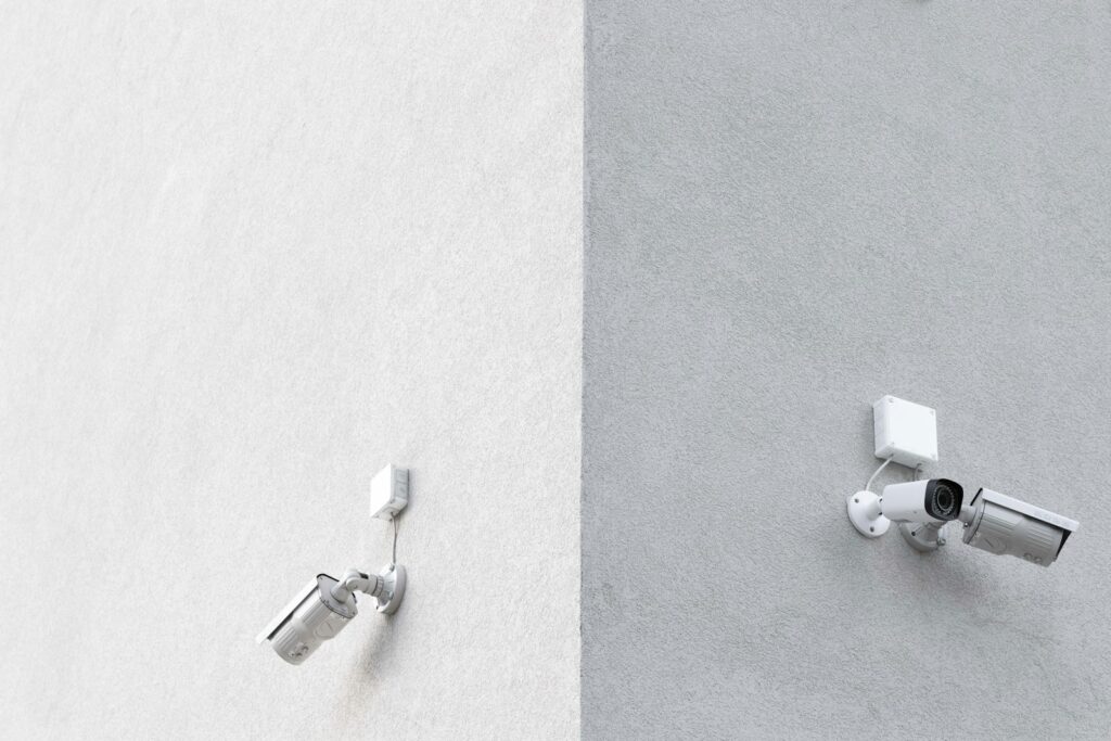 Three white CCTV cameras mounted on the wall at the corner of a building