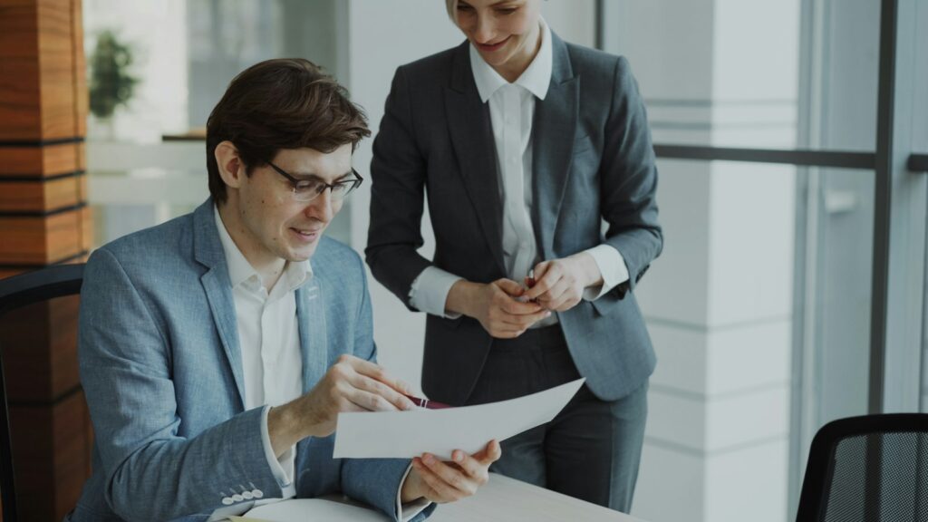 Two business colleagues reviewing documents together at a table in a modern office