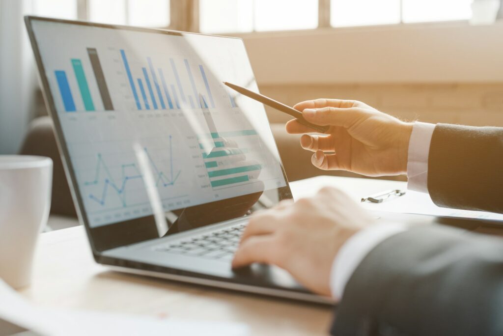 Person analysing business charts on a laptop while working through collected data