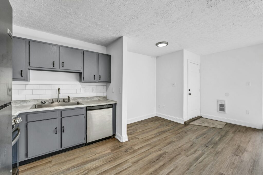 Kitchen with grey cabinets, white subway tiles and wood-look flooring