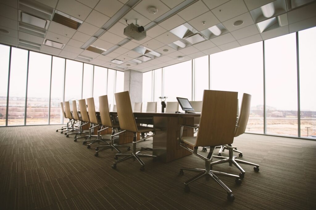 Oval wooden conference table surrounded by chairs in a minimalist boardroom, ready for a meeting