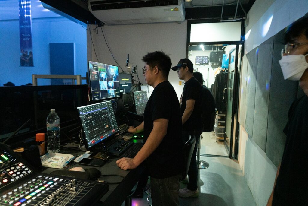 People working at a control desk surrounded by multiple monitors and audio equipment