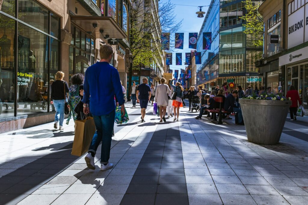 People walking along a shopping street between buildings during the day